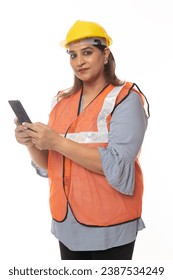 Female constructor using cell phone. Wearing hardhat and worker apron while isolated on white studio background.