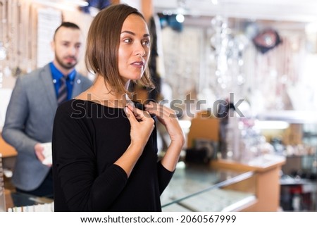 Female consumer trying chainlet with pendants in the jewelry shop