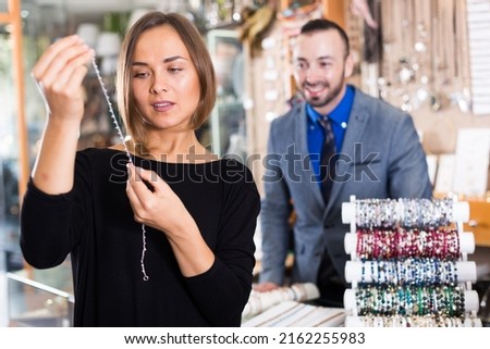 Female consumer trying chainlet with pendants in the jewelry shop