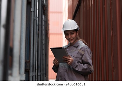 Female container yard worker loading containers box at commercial dock site. Female worker control loading container box from cargo freight ship for import export