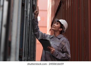Female container yard worker loading containers box at commercial dock site. Female worker control loading container box from cargo freight ship for import export