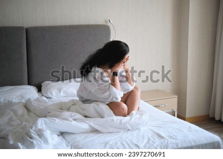 Female in contemplation amidst bedroom disarray, a picture of worry. Speaks to the modern issue of balancing life's demands.