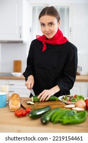 Female Cook In Black Uniform Chopping Vegetables