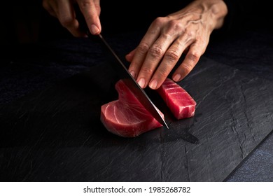 Female cook preparing a piece of bluefin tuna to make sushi on a blackboard. Asian food concept - Powered by Shutterstock