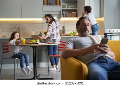 Female Cooking And Working At Laptop In Kitchen