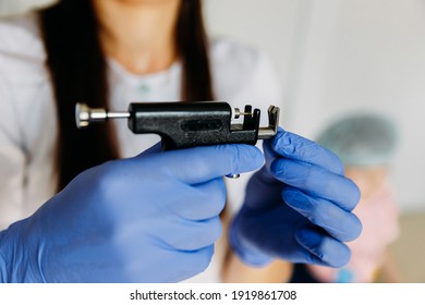 Female Cosmetologist Holding Ear Piercing Gun.