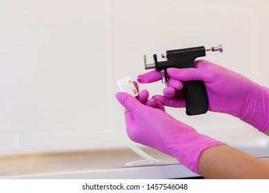 Female Cosmetologist Holding Earrings And Ear Piercing Gun