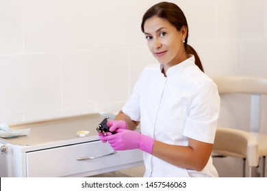 Female Cosmetologist Holding Earrings And Ear Piercing Gun