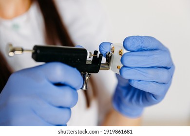 Female Cosmetologist Holding Earrings And Ear Piercing Gun