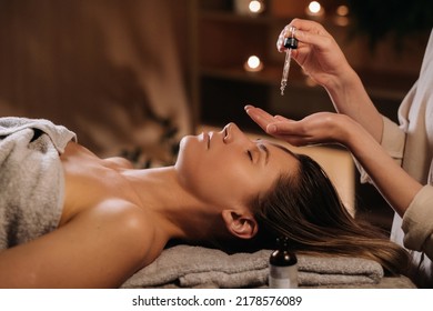A female cosmetologist holds a pipette with essential oil before aromatherapy and massage to the patient. aromatherapy.Close-up.
