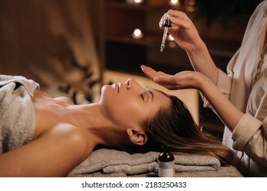 A female cosmetologist holds a pipette with essential oil before aromatherapy and massage to the patient. aromatherapy.Close-up. - Powered by Shutterstock