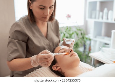 Female cosmetologist putting gel for cold hydrogenation before the cleaning procedure on face. Loosening and separation of the stratum corneum, opening of pores, moisturizing and softening skin 