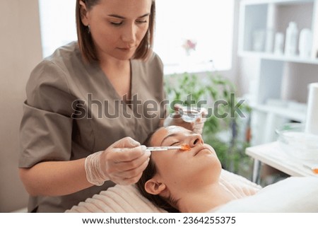 Female cosmetologist putting gel for cold hydrogenation before the cleaning procedure on face. Loosening and separation of the stratum corneum, opening of pores, moisturizing and softening skin 