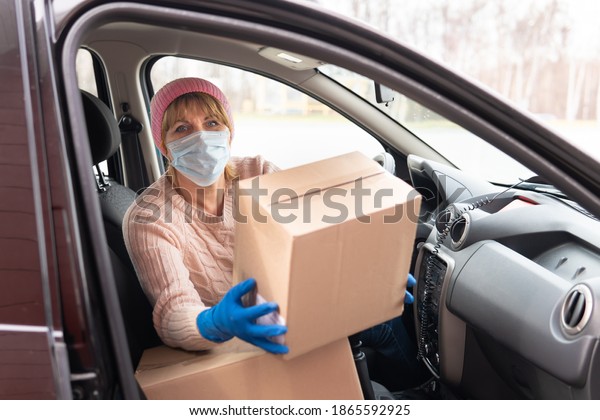 A female courier delivers boxes in the car. She\'s\
holding an order.