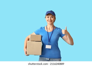 Female courier with parcels showing thumb-up on color background