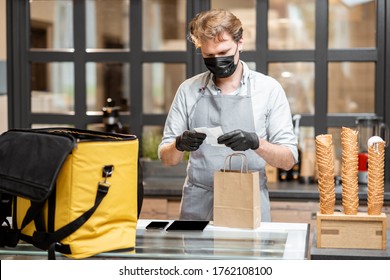 Female Courier Taking Online Order For Delivery At The Counter With Salesperson In The Small Pastry Shop Or Cafe. Concept Of A Take Away Food During Pandemic