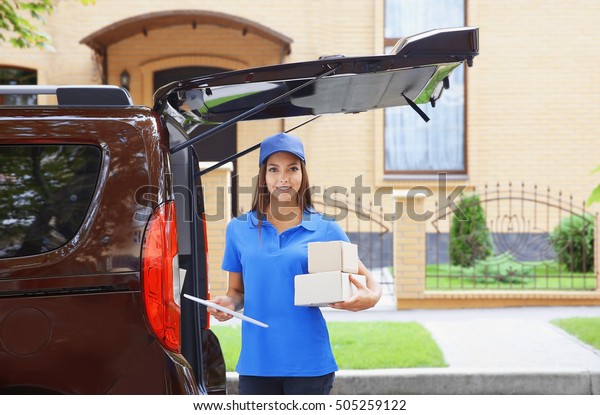 Female\
courier in uniform delivering parcels\
outdoor