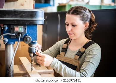 Female Craftman Is Working With A Drill Press, Worker Is Using A Drill Press In A Workshop Or Carpentry