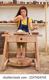 Female Craftsman Wets Her Hands In A Bowl Of Water To Form Clay. Vertical Photo