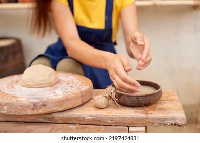 Female Craftsman Wets Her Hands In A Bowl Of Water To Form Clay