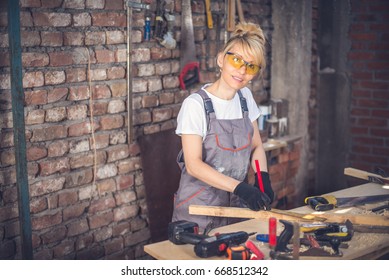 Female Craftsman,in Her Workshop,blonde With Protective Glasses And Work Suit