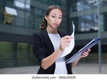 Female Creative Director Is Examining Documents Before Signing Outdoors.