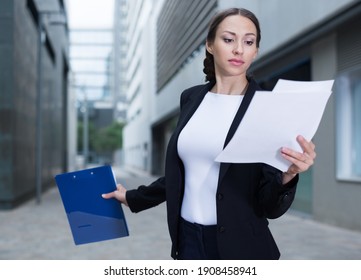 Female Creative Director Is Examining Documents Before Signing Outdoors.