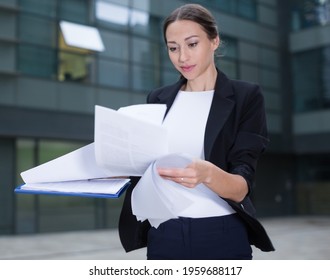 Female Creative Director Is Examining Documents Before Signing Outdoors.