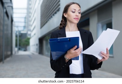 Female Creative Director Is Examining Documents Before Signing Outdoors.