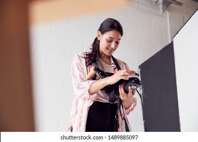 Female Crew Member On Video Film Set Operating Wireless Follow Focus Module In White Studio