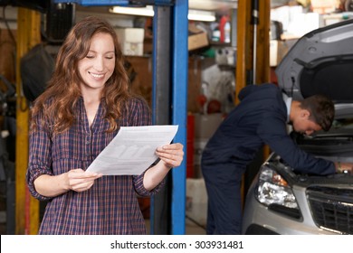 Female Customer In Auto Repair Shop Satisfied With Bill For Car Repair - Powered by Shutterstock