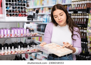 Female customer chooses face powder in a cosmetic store