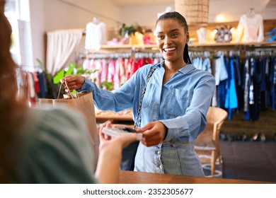 Female Customer In Fashion Store Paying For Clothes With Contactless Card Payment - Powered by Shutterstock