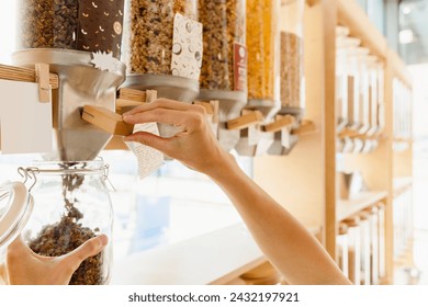 Female customer filling dry cereals in glass jar from dispenser at zero waste shop. Sustainable shopping in modern plastic free grocery store. - Powered by Shutterstock