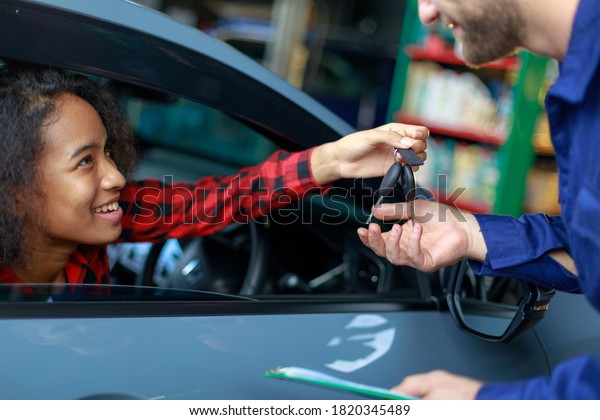 A\
female customer get car key from mechanic\
engineer.