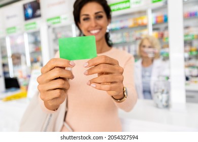 Female Customer Holding Loyalty Card In Pharmacy Store.