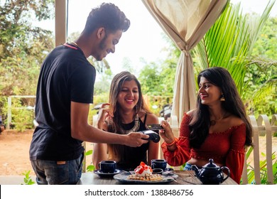 Female Customer Paying For Coffee, Pancakes With Credit Card Sitting With Laptop Online Shopping Black Friday Sale.the Waiter Payment Terminal While Client Doing Contactless Purchase In Cafe