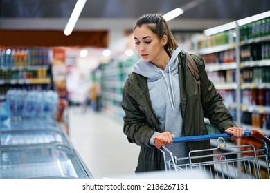 Female customer with shopping cart buying frozen food in supermarket.  - Shutterstock ID 2136267131
