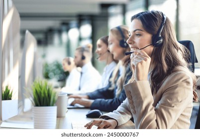 Female customer support operator with headset and smiling, with collegues at background - Powered by Shutterstock