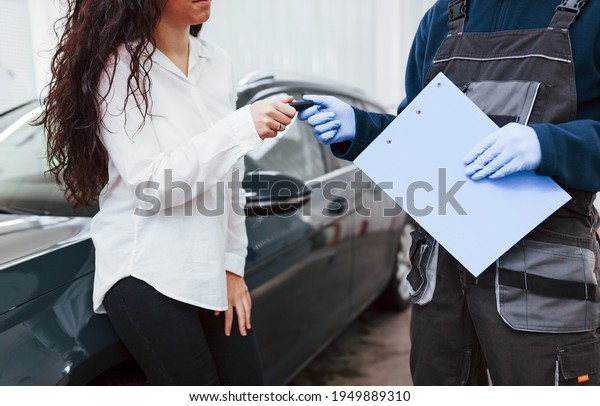 Female customer takes back her auto in car\
washing service.
