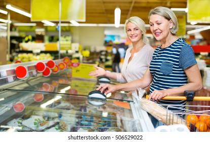 Female customers standing near display with a frozen food in the supermarket 