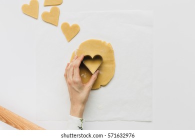 Female Cutting Out Heart Shaped Biscuit On White Table