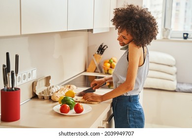 Female cutting vegetables on the board during the phone call