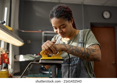 Female Cycling Master Fixing Bike Tube In Bicycle Workshop. Young Smiling African American Girl With Tattoos. Bike Service, Repair And Upgrade. Garage Interior With Tools And Equipment