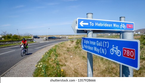 Female Cyclist Approaches Sustrans Cycle Path Sign In Outer Hebrides