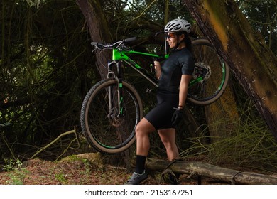 Female cyclist carrying her bike with one hand as she crosses a forest - Powered by Shutterstock