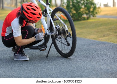 female cyclist fix the problem of mountain bike in park   - Powered by Shutterstock