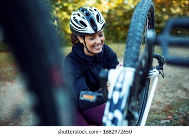 Female cyclist fixing bike outdoor - Powered by Shutterstock