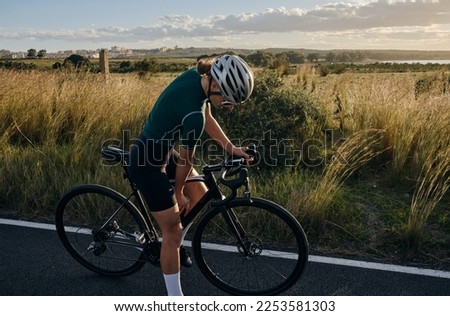  Female cyclist a gravel bike drinks water during exercise.Empty city road. Sports motivation.Murcia region in Spain