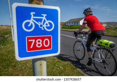 Female Cyclist Passes Sustrans Cycle Path Sign In Outer Hebrides